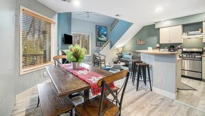 Une cuisine moderne dotée d’un four encastré, un coin repas avec une table et des chaises en bois, et un escalier menant à un niveau supérieur.