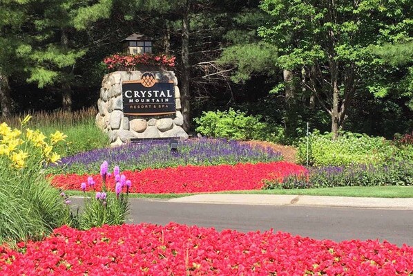 A sign for Crystal Mountain Resort & Spa with a stone base, surrounded by colorful flower beds.