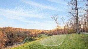Ein Golfplatz mit gewundenem Weg, umgeben von Bäumen und einem klaren Himmel.