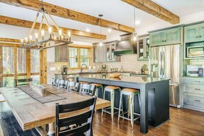 A modern kitchen with wooden beams, a large island, bar stools, and stainless steel appliances.