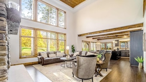 A spacious living area with a stone accent wall, large windows, a fireplace, and a dining area with a view of the outdoors. - Expansive dog-friendly home w/ golf course views, and nearby resort amenities (Thompsonville)