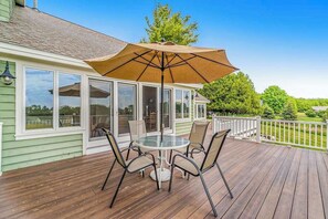 Une terrasse dotée d’une enceinte en verre, d’une table, de chaises et d’un parasol.