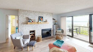 Un salon avec une cheminée, un canapé, une table basse et un balcon avec vue.