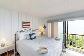 Ein Schlafzimmer mit einem Bett, einem Nachttisch, einer Lampe, einer Wanduhr und einem Fenster mit Blick.