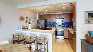 Une cuisine moderne avec des meubles en bois, un îlot central et un coin repas avec des chaises.