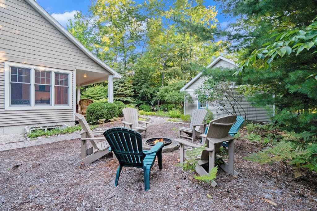 A patio with Adirondack chairs, a fire pit, and a small shed.