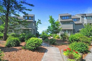 A residential area with modern houses, a wooden pathway, and well-maintained greenery. - Lakefront condo with deck, gorgeous view, fireplace, & W/D (Glen Arbor)