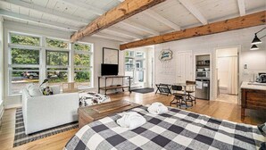 Et rummeligt værelse med en stor seng, en sofa, et spisebord og et tekøkken.