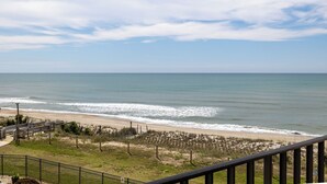 A beach view from a balcony with a railing, a sandy beach, and a clear sky. - Summer Winds 323 - 2 Bedroom Condo (Indian Beach)