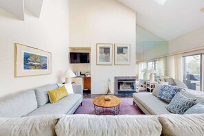 Ein modernes Wohnzimmer mit Kamin, einer Sofagarnitur und Kunstwerken an den Wänden.