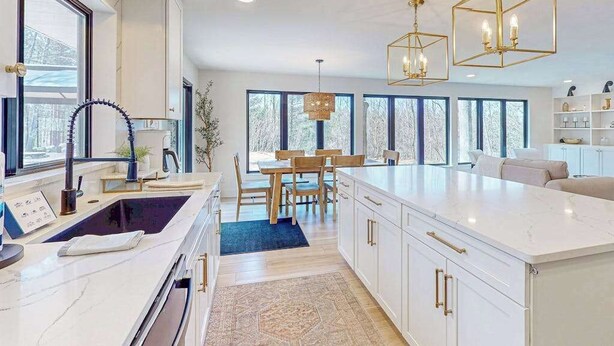 Una cocina moderna con armarios blancos, una isla grande e iluminación colgante.