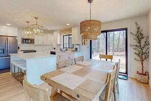 Eine moderne Küche mit weißen Schränken, einer zentralen Kochinsel und einem Essbereich mit Holztisch und Stühlen.