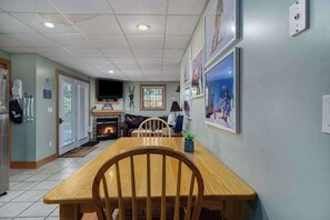 Un espace repas comprenant une table et des chaises en bois, une cheminée et des œuvres d’art accrochées aux murs.