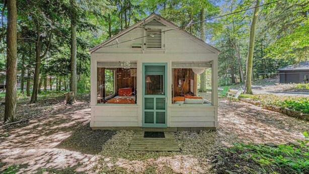 A small wooden cabin with a porch, surrounded by trees. - Peaceful & shady cottage near beach with streaming, free WiFi, full kitchen (Beulah)