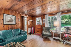 Una habitación con paneles de madera, un sofá de cuero verde, una silla y una mesa con una lámpara.