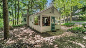 A small, single-story cabin with a porch, surrounded by trees. - Peaceful & shady cottage near beach with streaming, free WiFi, full kitchen (Beulah)