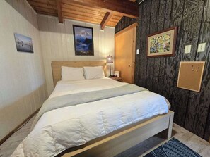 Ein Schlafzimmer mit einem hölzernen Bett, einem Nachttisch, einer Lampe und einem gerahmten Bild an der Wand.