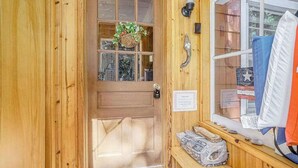 A wooden door with a window, a hanging plant, and a bench with items on it. - Lake home close to the water with WiFi, firepit, washer/dryer (Beulah)