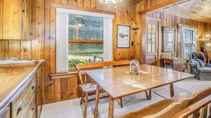 A wooden interior with a dining table, chairs, a bench, a chandelier, and a large window. - Lake home close to the water with WiFi, firepit, washer/dryer (Beulah)