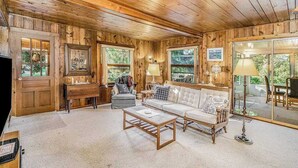 A log cabin interior with a sofa, coffee table, and a fireplace. - Lake home close to the water with WiFi, firepit, washer/dryer (Beulah)