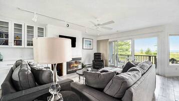 A modern living room with a fireplace, a sofa, a coffee table, and a ceiling fan.