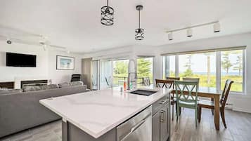 A modern kitchen with a central island, stainless steel appliances, and a dining area with a table and chairs.
