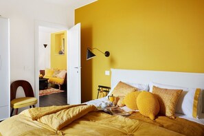 A room with a bed, a chair, a lamp, and a doorway leading to another room. - La Camerata - One Bedroom Villa, Sleeps 2 (Spello)
