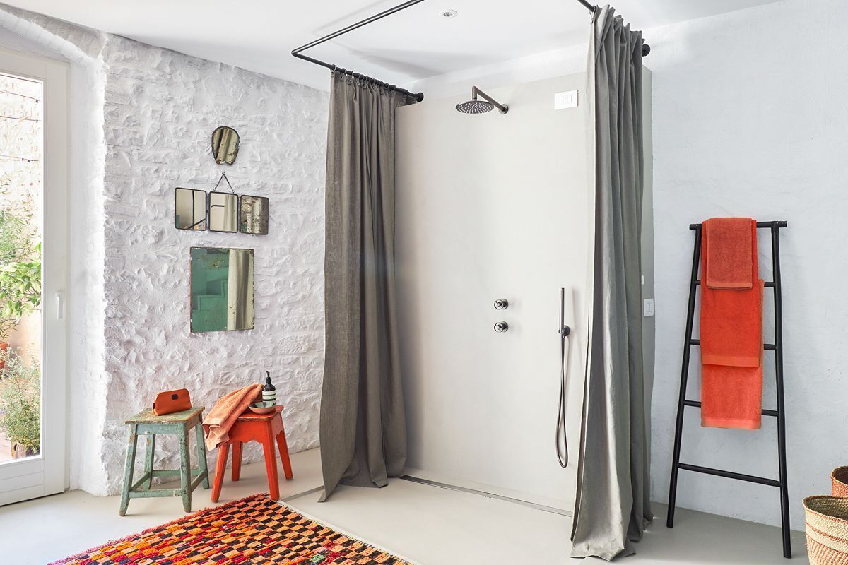 A modern bathroom with a shower, a towel rack, and a small stool.