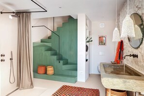 Un baño con escalera verde, lavamanos de piedra y ducha.