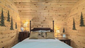 Une chambre de style cabane en bois, avec un lit, deux tables de chevet et des lampes fixées au mur.