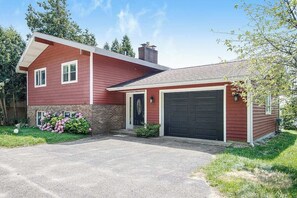 Ein zweistöckiges Haus mit Garage, einer Ziegelbrütung und einem Vorgarten mit Blumen.