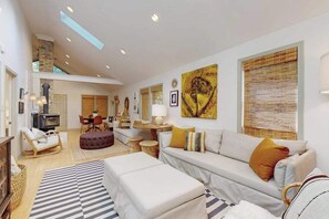 A spacious living area with a sofa, ottoman, and a dining table.