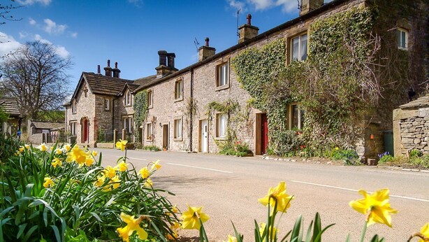 A row of stone buildings with a clear road in front, surrounded by daffodils. - Heatherstone House - Six Bedroom Villa, Sleeps 10 (Broughton)