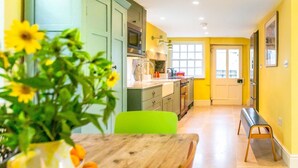 A kitchen with a dining area, a bench, and a door leading to another room. - Heatherstone House - Six Bedroom Villa, Sleeps 10 (Broughton)