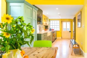 A kitchen with a dining area, a bench, and a door leading to another room. - Heatherstone House - Six Bedroom Villa, Sleeps 10 (Broughton)