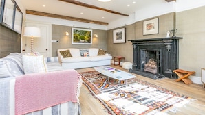 A living room with a sofa, a coffee table, a fireplace, and a rug. - Heatherstone House - Six Bedroom Villa, Sleeps 10 (Broughton)