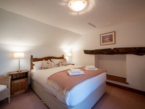 Una camera da letto con un letto, due comodini con lampade, una testata in legno, un quadro appeso al muro e un camino in pietra.