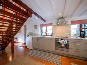 Eine moderne Küche mit einer Holztreppe, Edelstahlgeräten und einem Fenster mit Blick.