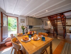 Zona pranzo con tavolo in legno, sedie e articoli per la colazione.