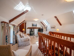 Ein gemütliches Schlafzimmer im Loftsstil mit schrägem Dach, Holzbalken, Kamin, Fernseher und einem Balkon mit Blick.