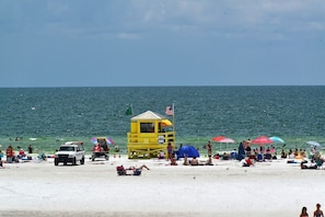 Ein Strand mit einem Rettungsturm, Sonnenschirmen und entspannten Personen.