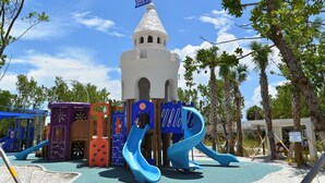 Ein Spielplatz mit Rutschen und einer Burgähnlichen Struktur.