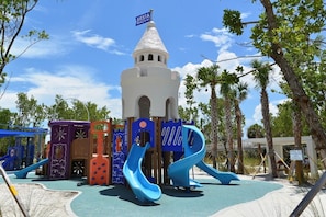 Ein Spielplatz mit Rutschen und einer Burgähnlichen Struktur.