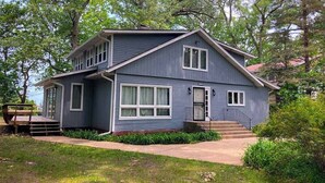 A two-story house with a front porch, a staircase, and a small deck. - Family-friendly Home w/ Lake Views, Free WiFi & Private Beach Access (Union Pier)