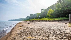 A sandy beach with a wooden fence and trees in the background. - Family-friendly Home w/ Lake Views, Free WiFi & Private Beach Access (Union Pier)