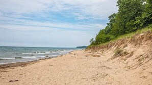 Une plage avec un rivage sablonneux et une falaise herbeuse.