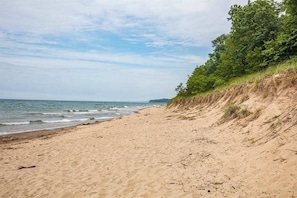 A beach with a sandy shore and a grassy cliff. - Main Home & Cozy Guest House w/ Two Full Kitchens & Free WiFi - Walk to Beach (Union Pier)