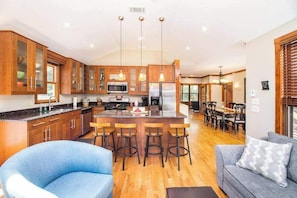 A modern kitchen with wooden cabinets, a central island with stools, and a dining area with a table and chairs. - Main Home & Cozy Guest House w/ Two Full Kitchens & Free WiFi - Walk to Beach (Union Pier)