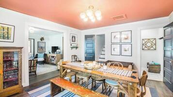 A dining area with a wooden table, chairs, and a bench. There are framed pictures on the walls and a cabinet with glass doors.