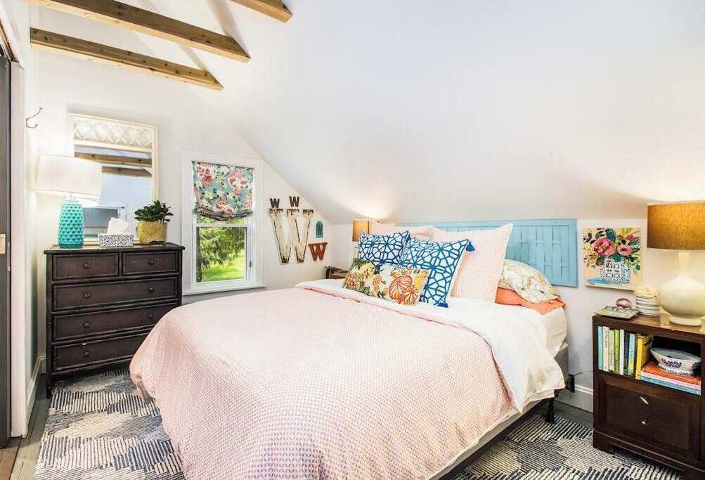 A bedroom with a bed, dresser, and a window.